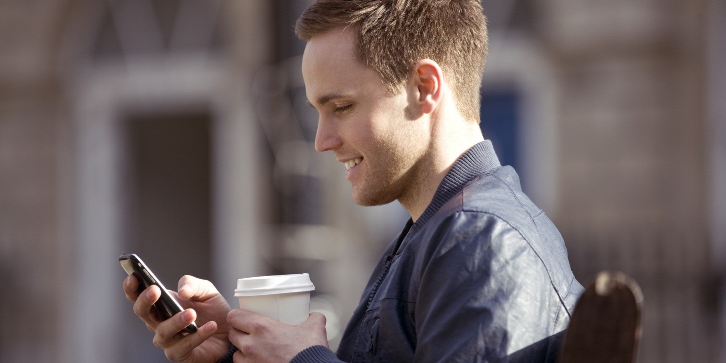 Man holding a coffee and a phone